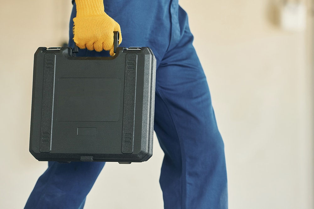 Holding case. Young man working in uniform at construction at daytime